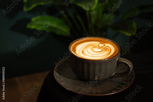 Hot latte coffee with latte art in a black cup on a table, a warm drink, a breakfast moment, or a coffee-themed visual.