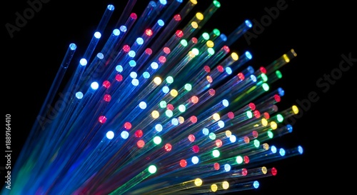 Close-up of illuminated fiber optic cables with multicolored light tips against a dark background, representing data transmission and telecommunications technology