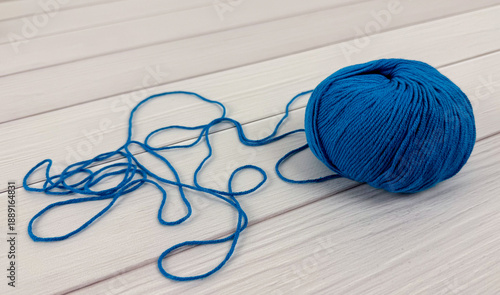 Photos Blue yarn ball with loose strand on white wooden background