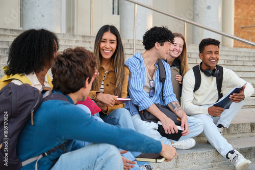 Happy multi ethnic students sitting on steps, enjoying conversation and friendship outside university