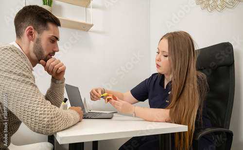 Valokuva Female dentist educating male patient with dental model during oral health consu