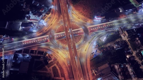Drone view of nighttime car lanes, highway, and intersections in the city, city road, car lanes, expressway between buildings, traffic flow on city road, expressway and highway, traffic junction car