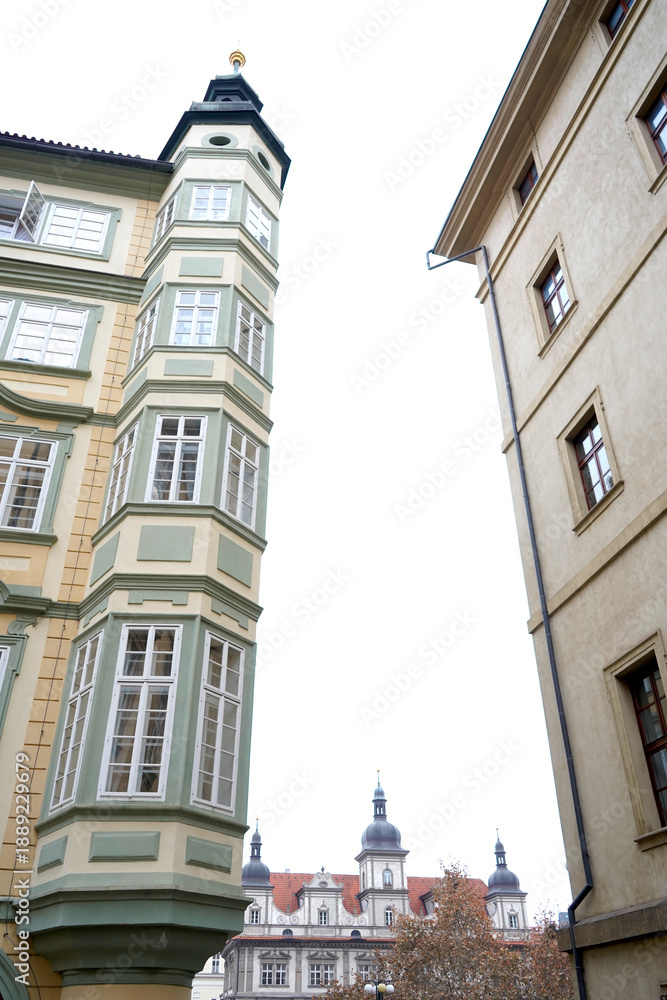 Obraz premium Narrow street view between historic buildings with tall ornate facade and tower detail, upward perspective showing classic architecture and quiet urban atmosphere.