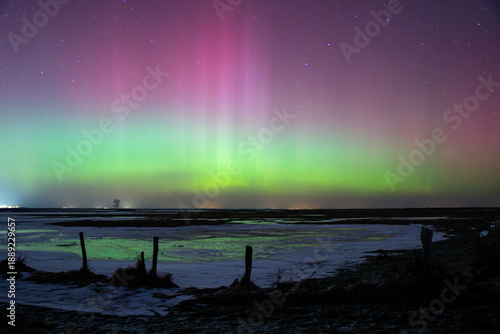 Red and Green Aurora Borealis over an Icy Meadow near Greifswald at Night