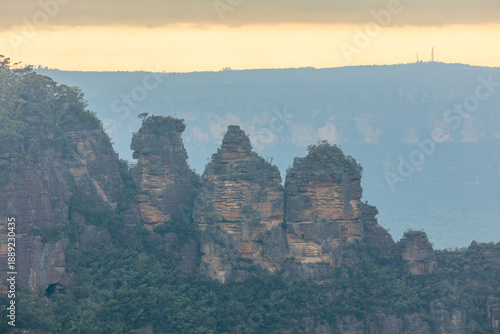 Photograph of the famous Three Sisters rock formation at sunrise at Echo Point in the town of Katoomba in the Blue Mountains in New South Wales, Australia.