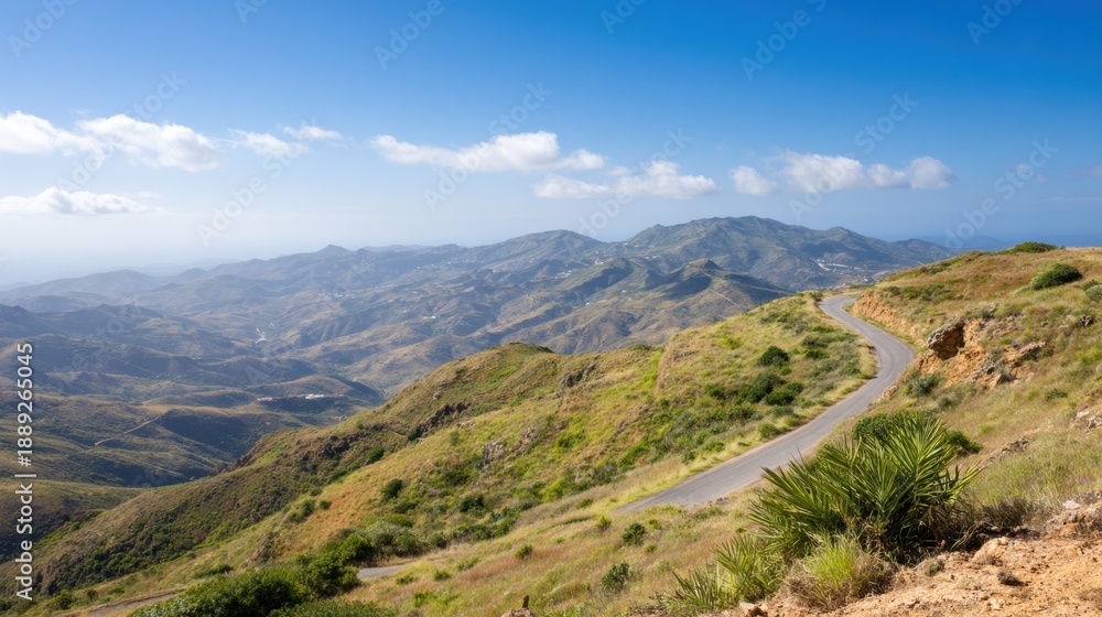 Fototapeta premium Scenic winding road through hills with mountains in the distance
