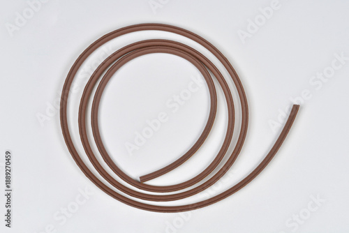 A brown adhesive foam strip for window sealing shown in a gentle curve on a clean white background with its yellow backing paper visible