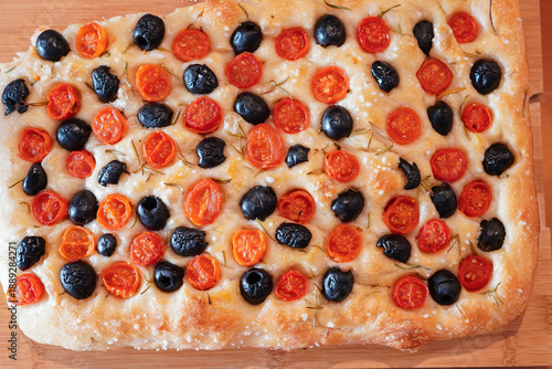Bird's-eye view of homemade Italian focaccia with black olives, cherry tomatoes, and rosemary