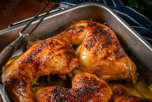 Baked chicken legs in metal baking dish.