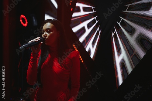 Bild auf Leinwand Female singer performing live with microphone in spotlight