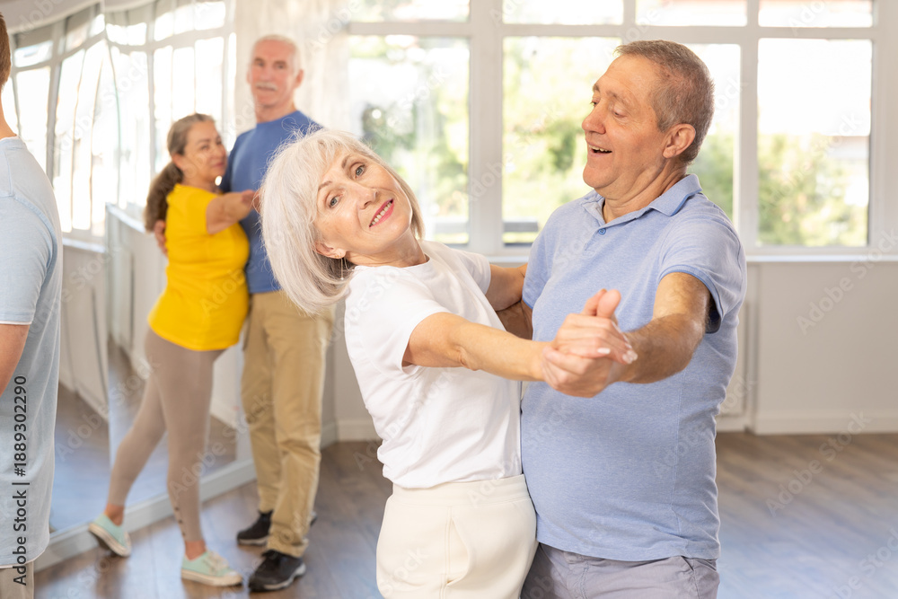Fototapeta premium Couple of elderly man and elderly woman dancing waltz in studio