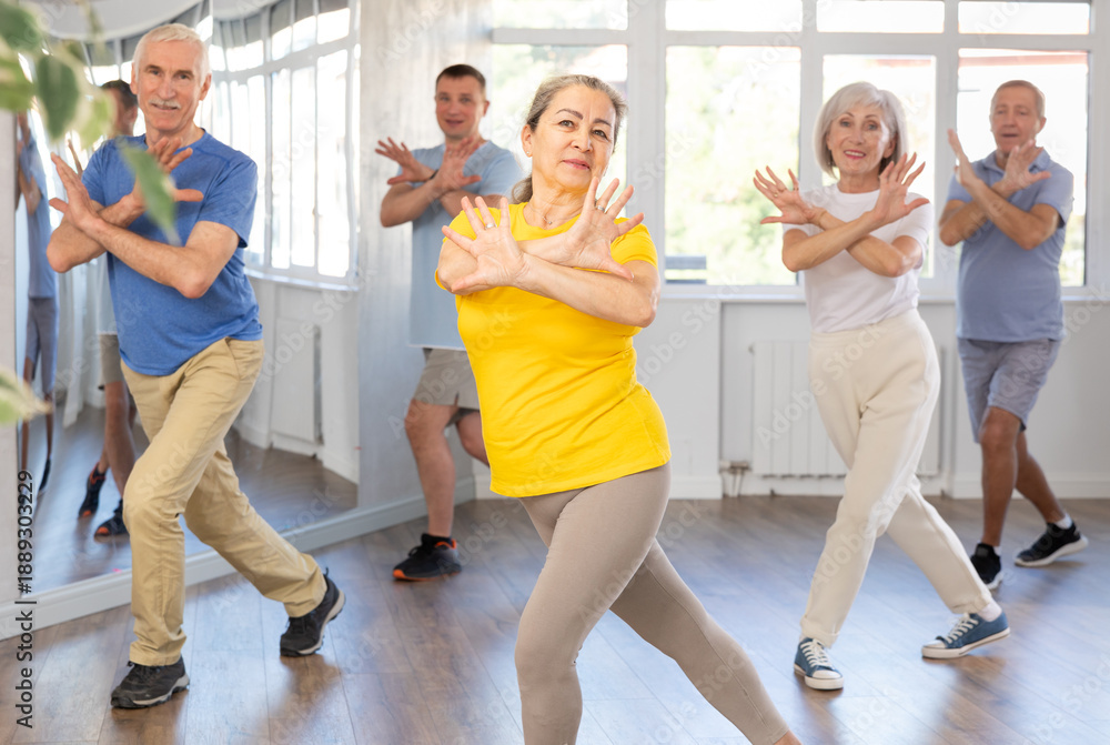 Fototapeta premium Elderly woman rehearsing modern dance in group in dance studio