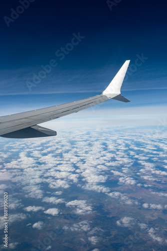 Airplane wings extend above white clouds, providing clear view of  atmospheric layers and sense of altitude during the flight, air transportation