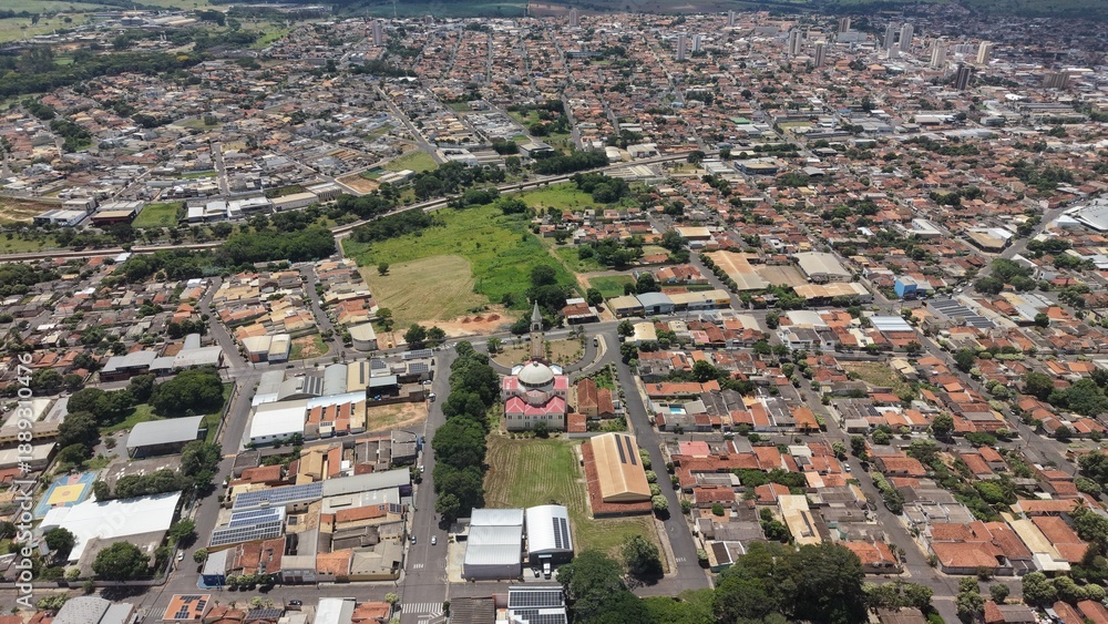 Fototapeta premium Aerial view of a bustling city with residential and commercial buildings. The cityscape shows a dense urban environment with a combination of buildings, streets, and green spaces