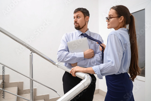 Fotografi Business woman pulling man's necktie on stairs in office