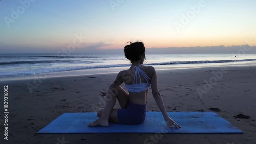 Young woman practicing yoga on the beach at sunrise