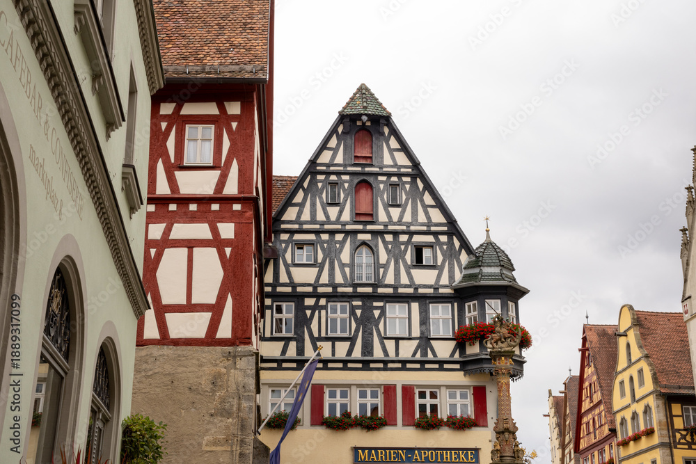Fototapeta premium Market Square of Rothenburg ob der Tauber, Germany, with historic Town Hall Tower, Ratstrinkstube Clock Tower, half‑timbered houses, cobblestone streets, fountain and shops in medieval Bavarian town.