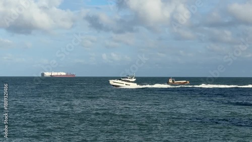 Several cargo ships and ferries anchored in Panama Bay, with shipping traffic on a sunny day against a cloudy backdrop