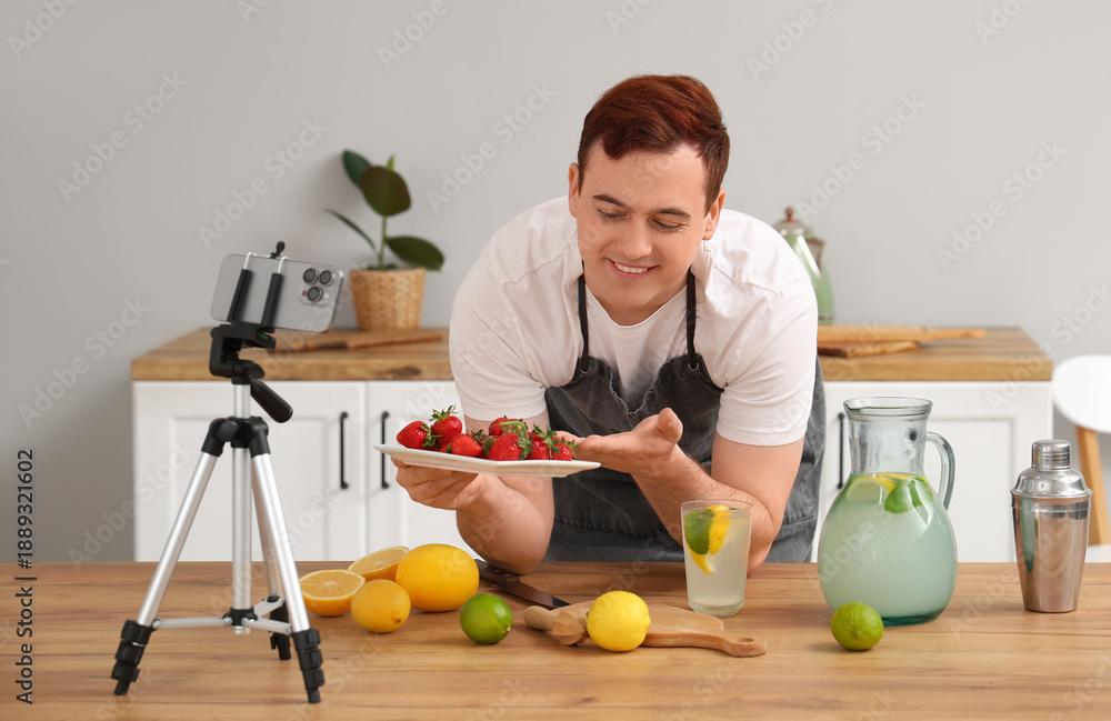 Fototapeta premium Young man recording video of him making homemade lemonade in kitchen