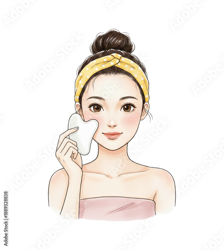 Asian woman happily doing gua sha facial massage with a white tool wearing a yellow headband and pink towel looking cheerful and relaxed