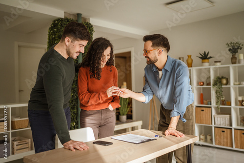 Bild auf Leinwand Real estate agent handing over keys to young couple
