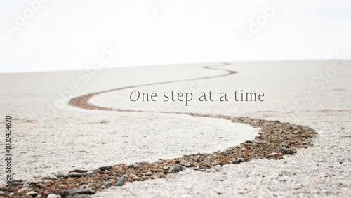 A Winding Path of Gravel and Sand with the Text One Step at a Time in a Minimalist Setting