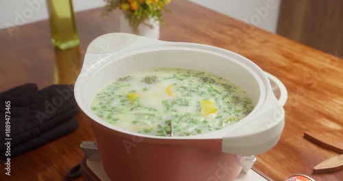 Soup broccoli is simmering on a gas stove, steam rising from the pot during cooking. Close-up of boiling homemade soup on a gas cooker, natural light, traditional kitchen style home cooking process.