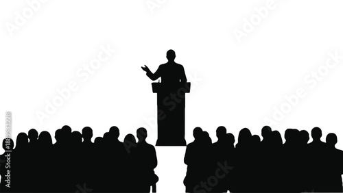 A speaker stands at a podium addressing a large audience in silhouette