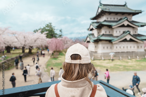 Woman tourist sightseeing Hirosaki Castle with Sakura Cherry Blossom in Spring, happy traveler travel in Hirosaki city, Aomori, Tohoku, Japan. Landmark famous in Japan. Travel and Vacation destination