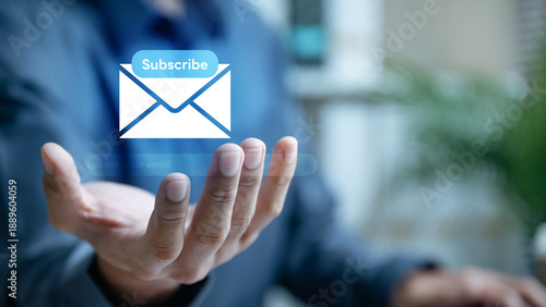 Digital newsletter subscription concept with email icon and subscribe button above hand. Represents signup form, call to action, email marketing campaign, lead generation, customer engagement.