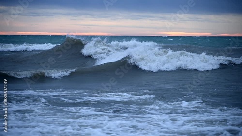 Waves Crash on the Shore During a Storm at Sunset With Clouds and Wind, Showing Nature's Power in Slow Motion