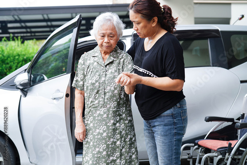 Caregiver help Asian elderly woman disability patient get in her car.