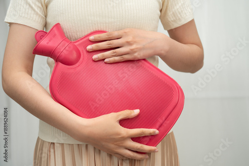 Woman using hot water bottle to relieve menstrual abdominal pain.