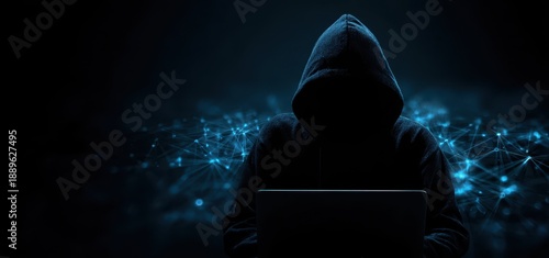 Hacker in dark hoodie using laptop with abstract data network background representing cybercrime and data breach