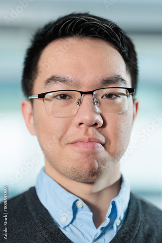 Close up headshot of a young Asian man with a neutral expression, ideal for employee profiles, business directories, or professional networking concepts.