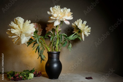 Floral still life - branches of flowering peonies in a vase. Theatrical stage lighting