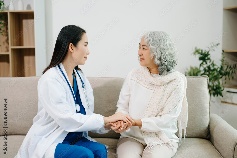 Obraz premium Female doctor supporting elderly woman at home during medical visit. Senior healthcare, home care, patient support, wellness, trust and professional medical assistance concept.