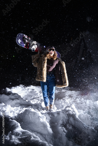 Foto at night in a snowstorm with a snowboard and a pretentious fur coat