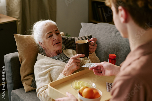 Foto Senior Caucasian woman reclining on sofa holding mug, while young adult Caucasia