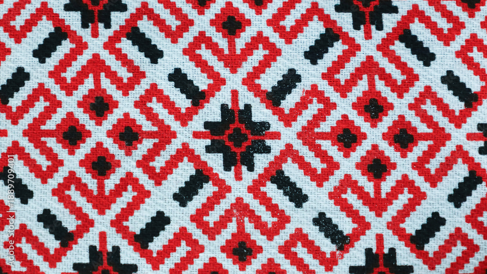 Obraz premium Intricate Mirukser textile pattern showcasing vibrant red and black designs on a white backdrop in natural light