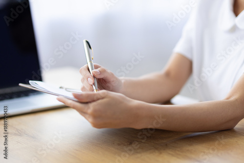 Close Up of Woman Writing Notes on Clipboard at Desk