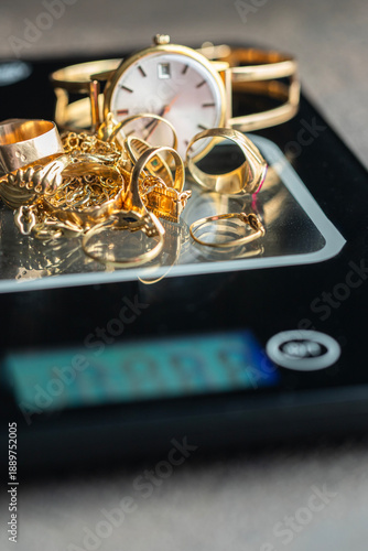 Gold rings, chains, and a watch on a digital scale represent the concept of selling gold for cash, appraisal, and jewelry evaluation in pawnshops and gold exchange services. © vasanty