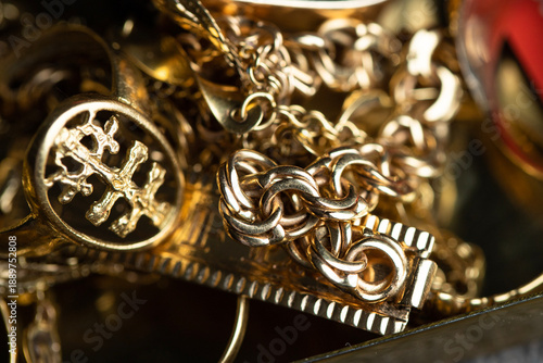 Close up of A pile of golden rings, chains, and a watch reflects the idea of pawnshops and gold buyers evaluating jewelry for cash payments.