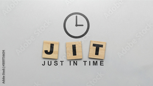 Business concept for Just-In-Time (JIT) manufacturing and logistics. Wooden letter tiles spelling JIT with a clock icon and the full phrase on a grey textured background