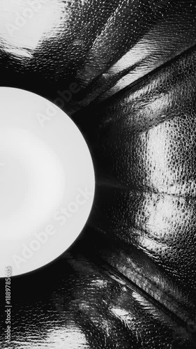 surreal monochrome light orb shining through dimpled foil tunnel with reflective textures and dramatic depth