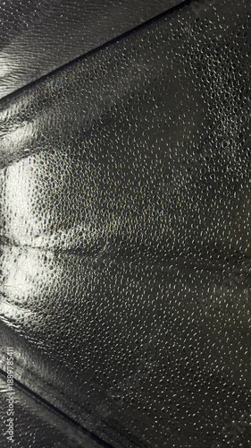 mesmerizing black iridescent bubble texture closeup panning shimmering holographic material sparkling under soft dim light abstract futuristic pattern