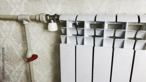 hand turning thermostatic radiator valve in vintage floral interior for winter home heating control