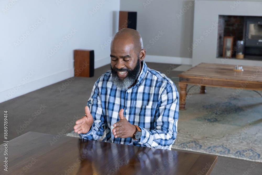 Fototapeta premium Senior african american man wearing wristwatch talking and gesturing at living room table