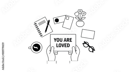 A person holding a sign that says you are loved surrounded by office supplies
