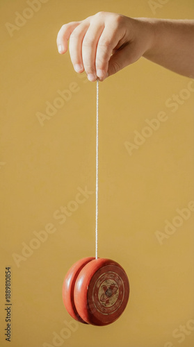 Hand holding a red yo-yo on a yellow background